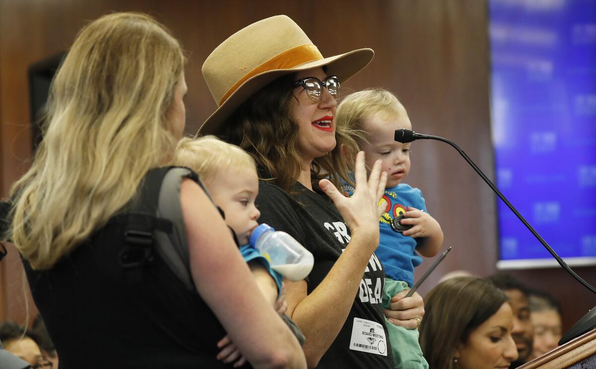 Northeast L.A. Climate Collective members Emily Spokes, right, and Carolina Forni, left, with Carolina's 1-year-old twins Grant and Clark, address the Los Angeles Department of Water and Power's board of commissioners Tuesday.