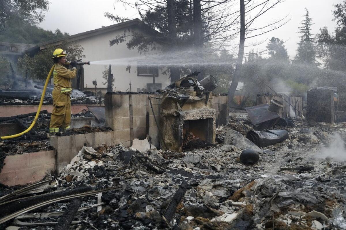 A firefighter hoses down a fire-ravaged home in Napa.