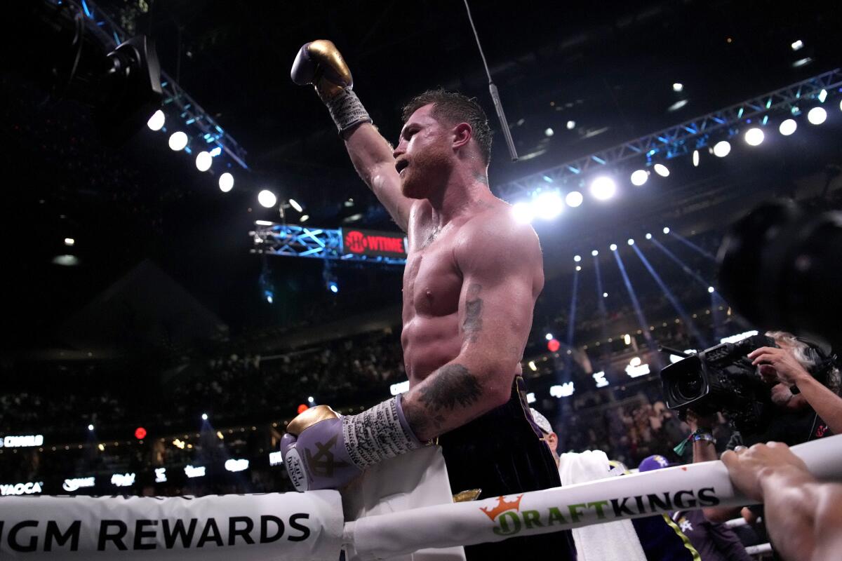 Canelo lvarez raises his right first in triumph in the ring after defeating Jermell Charlo.