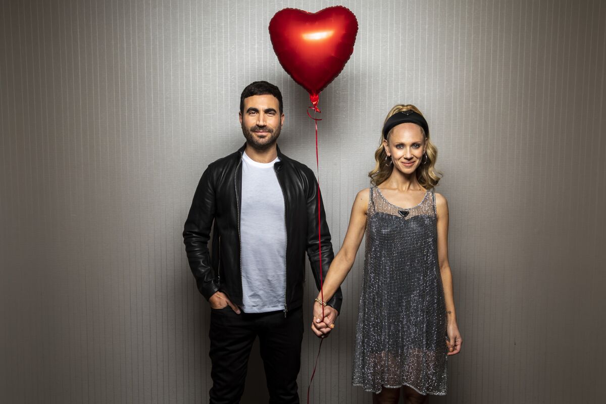 Actors Brett Goldstein and Juno Temple holds hands and a red balloon
