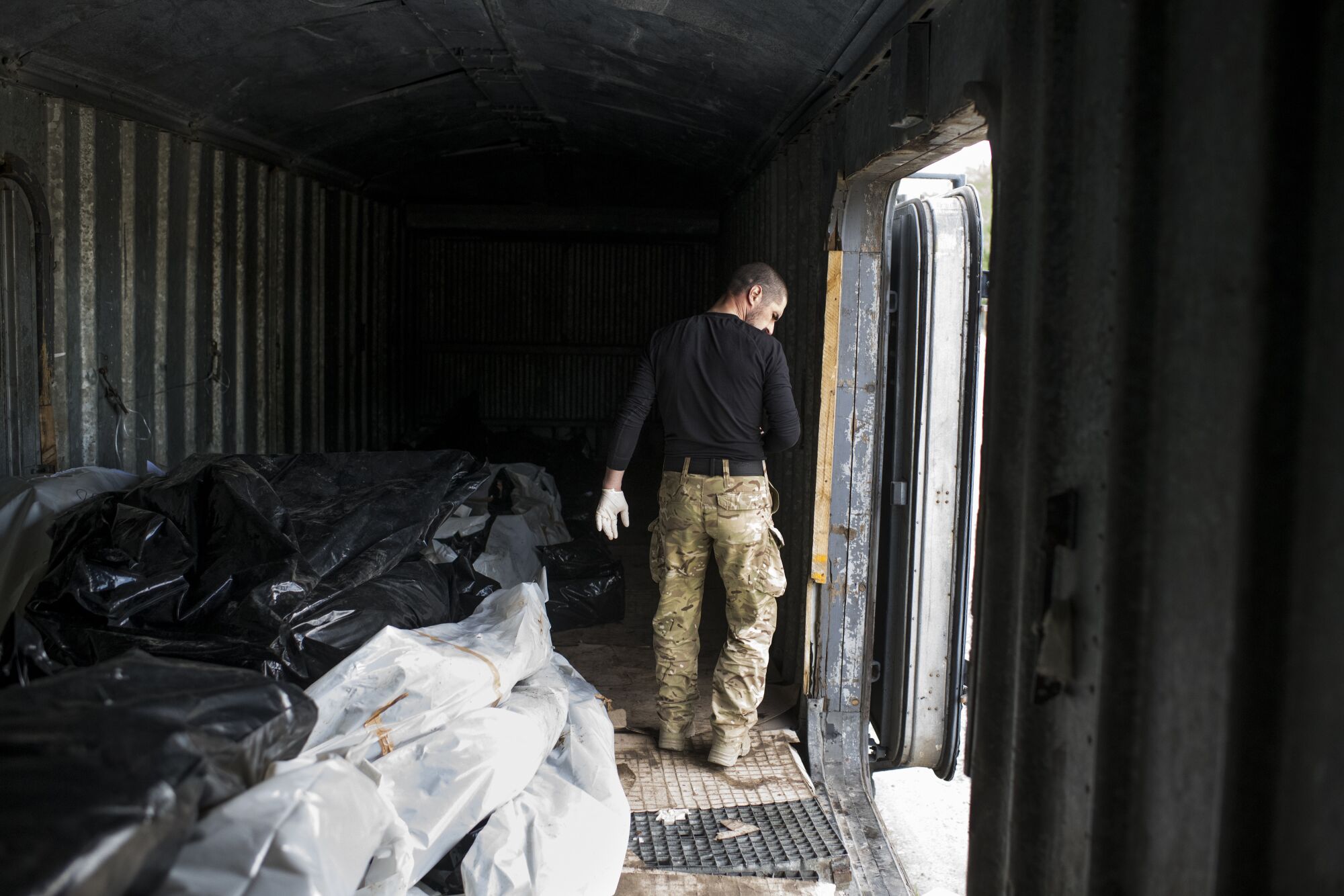 A man checks bodies in a refrigerated train used to store the remains of Russian soldiers