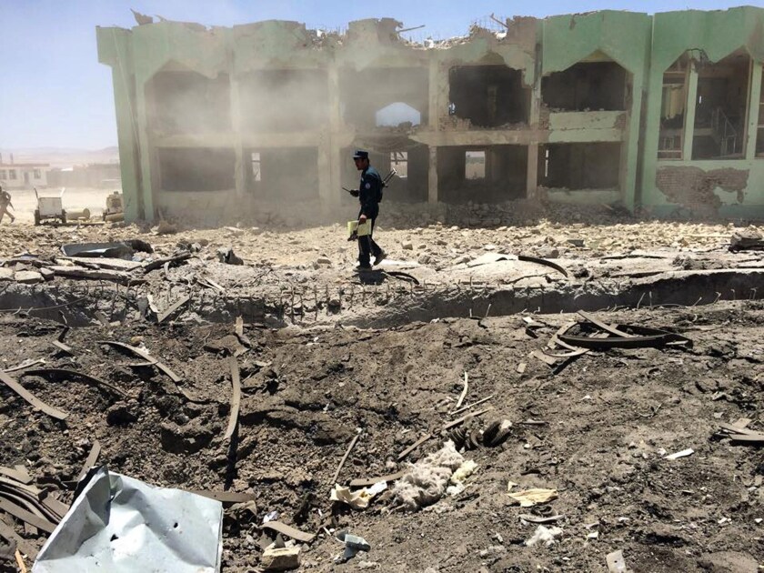 An Afghan policeman inspects the site of a suicide attack in Qalat on May 25. A Taliban truck bomber detonated explosives outside a government complex, wounding more than 70 people.