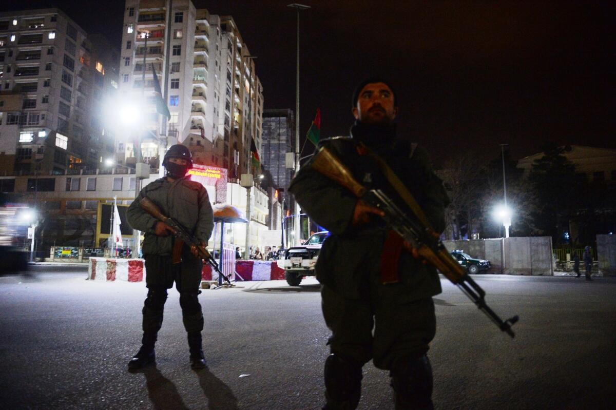 Afghan policemen block a road as they stand guard near the security perimeter set up around the Serena Hotel in Kabul, which was attacked by four gunmen late Thursday.