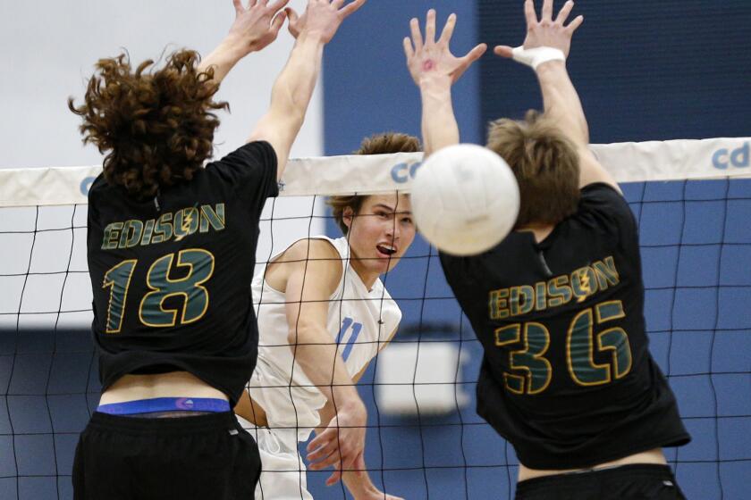 Corona del Mar's Sterling Foley (11) rips a kill past the blocks of Own Banner (18) and CJ Addison in a CIF Division-1 boys' volleyball playoff match against Edison on Wednesday.
