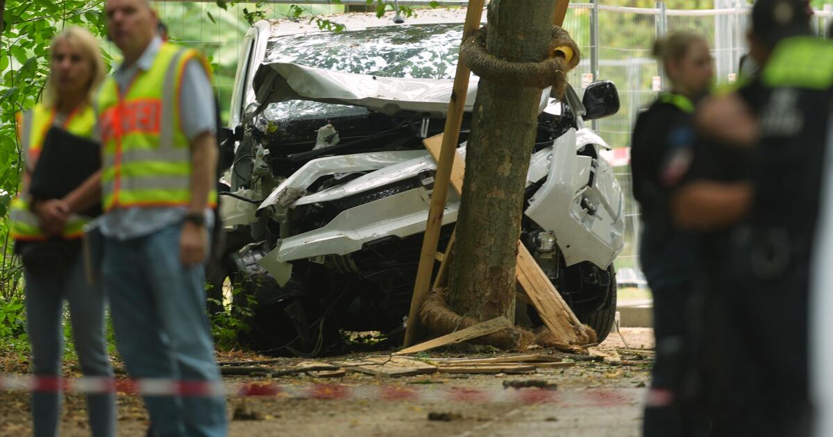 Photo: Los Angeles Times Police officers stand near a vehicle crashed into a tree after driving into a crowd near Berlin's annual Pride event, in