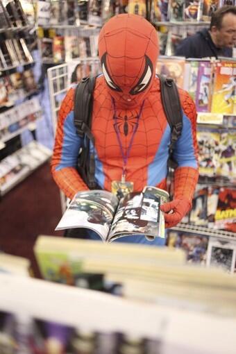 Corey Cuadrado, dressed as Spider-Man, browses the comics at Comic Con in New York on Friday, Oct. 8, 2010.