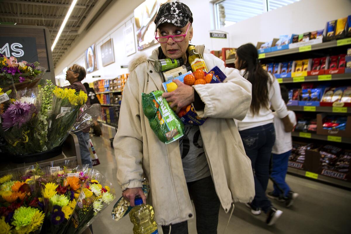 Janelle Myers of Riverside searches for her shopping basket with her arms filled with groceries during the grand opening of Aldi food market in Moreno Valley in March.
