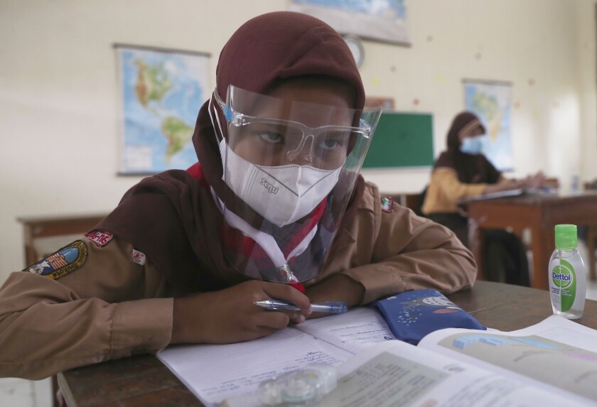 A student wearing a face shield sits spaced apart during a trial run of a class with COVID-19 protocols at an elementary school in Jakarta, Indonesia, Wednesday, April 7, 2021. (AP Photo/Tatan Syuflana)