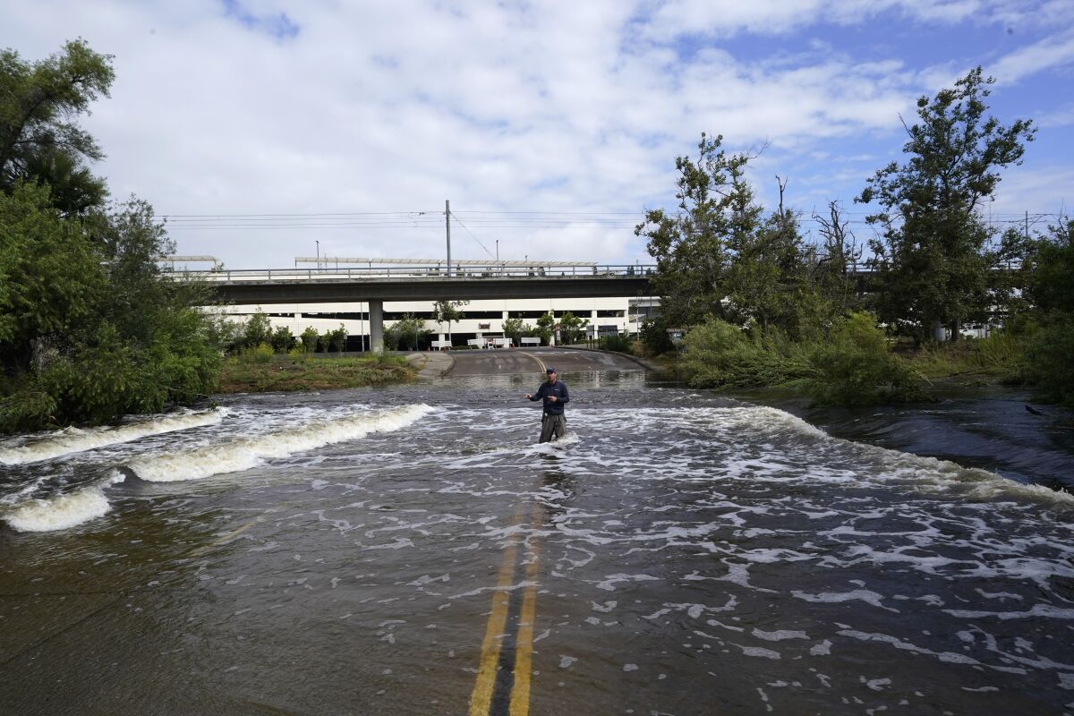 Un journaliste de télévision se tient sur une route inondée après le passage de la tempête tropicale Hilary lundi à San Diego.