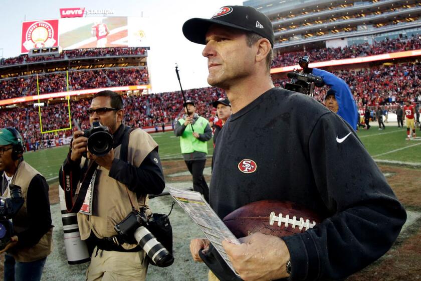 Jim Harbaugh carries the game ball off the field at Levi's Stadium after coaching the 49ers for the last time.