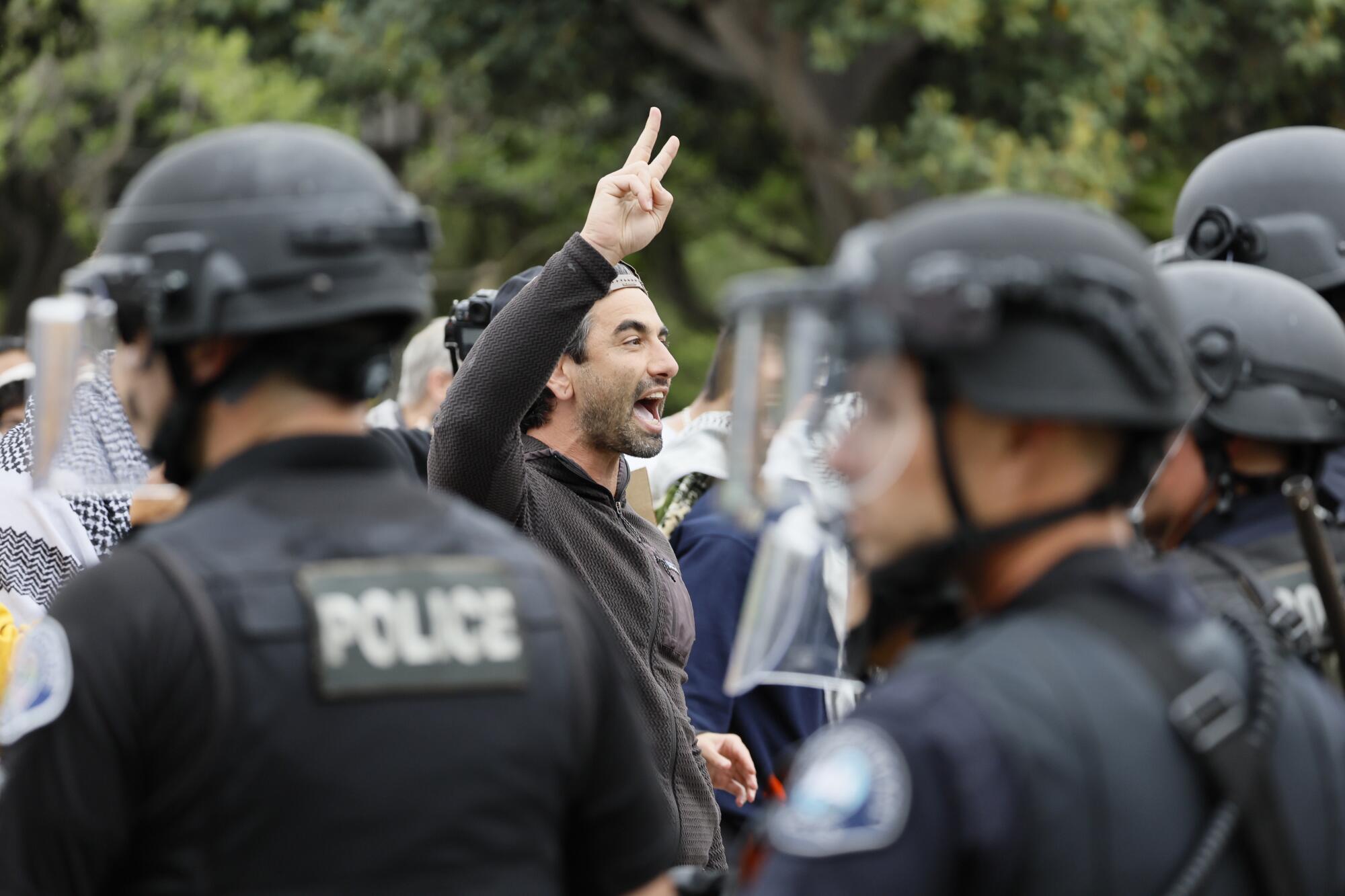 A pro-Palestinian demonstrator flashes a piece sign as a weeks-long pro-Palestine protest at UC Irvine.