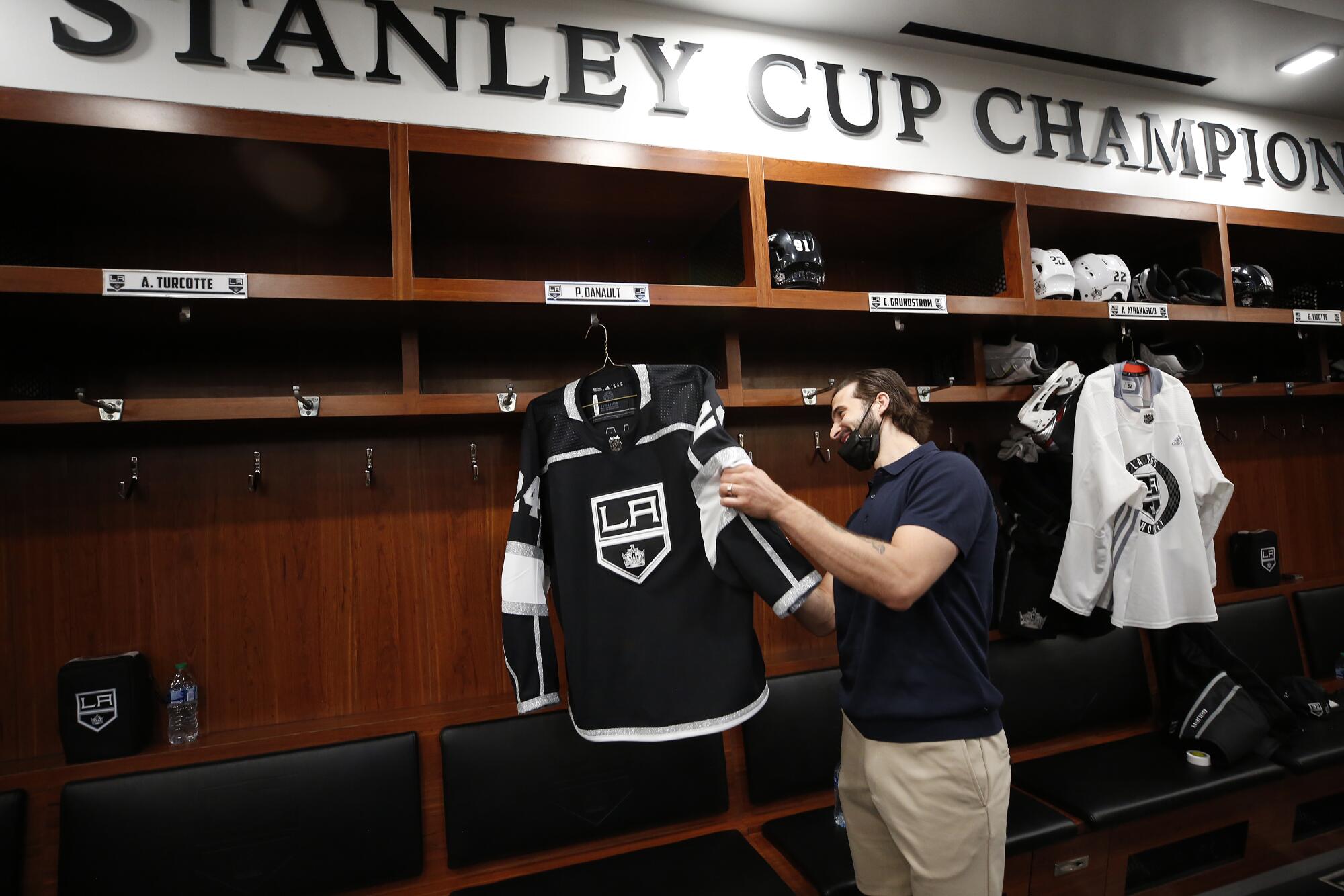 New Kings player Phillip Danault checks out his team jersey during a tour of the locker room.