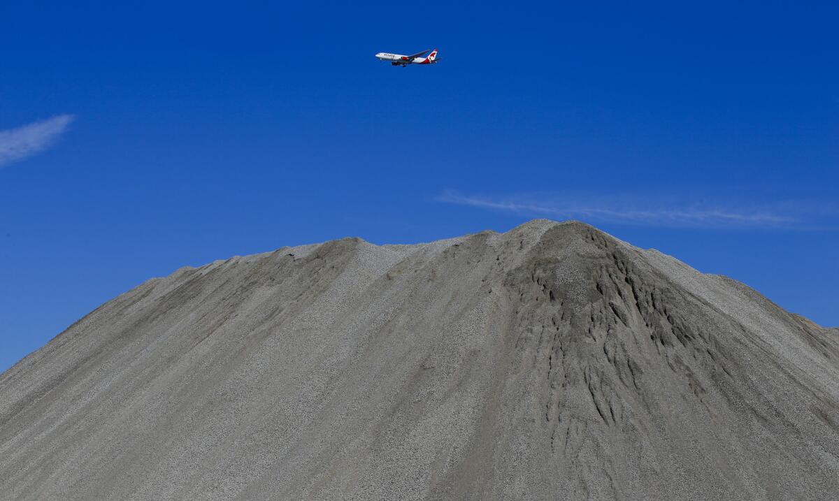 An airplane making its final approach to LAX flies over a hill of crushed concrete at the former Hollywood Park site in Inglewood where an NFL stadium will eventually be constructed.
