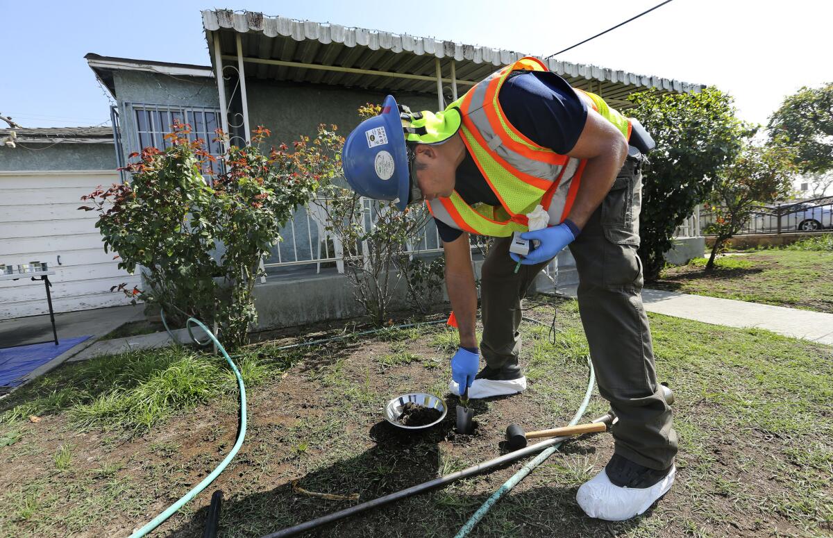 Glen Van Eekout, an environmental health specialist for the L.A. County health department, collects a soil sample from the front yard of a home in Commerce.