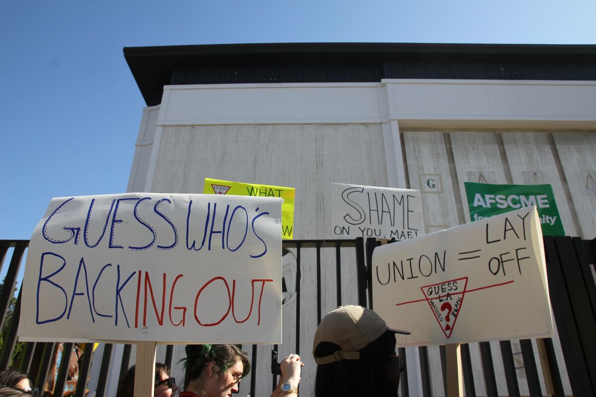 Workers protest outside the Marciano Art Foundation in 2019 with a sign that reads "Guess Who's Backing Out?"