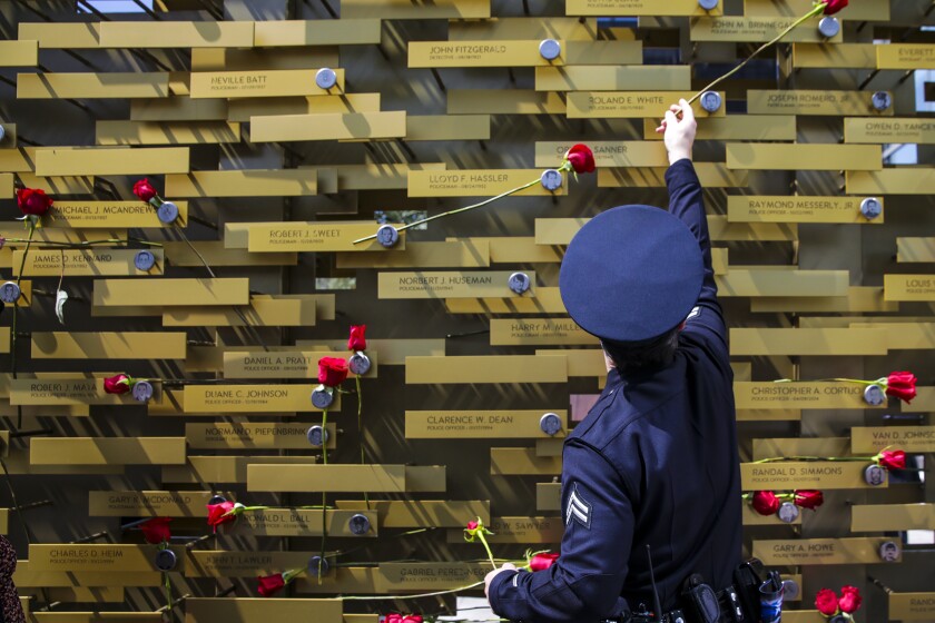 Los Angeles, CA - May 04: Officer Dylan Wells places flower at the memorial monument after a ceremony to honor the 238 LAPD officers killed in the line of duty over the years, held at LAPD headquarters on Wednesday, May 4, 2022 in Los Angeles, CA. (Irfan Khan / Los Angeles Times)