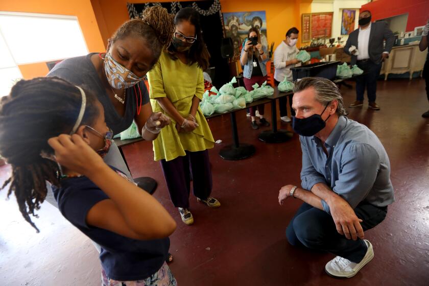 LOS ANGELES, CA - JUNE 03, 2020 - - California Governor Gavin Newsom, right, listens as he is introduced to Kirikou Muldrow, 8, by California Senator Holly Mitchell and California Assembly Member Sydney Kamlager-Dove, right, during a visit to the Hot and Cool Cafe in Leimert Park after several days of protest in Los Angeles on June 3, 2020. The cafe has been providing meals for senior citizens 3 days a week during the coronavirus pandemic stay at home order. Muldrow has been helping pack the meals. Her mother is co-owner of the the cafe. (Genaro Molina / Los Angeles Times)