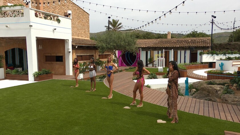 Female reality show contestants stand lined up outside a Spanish villa.