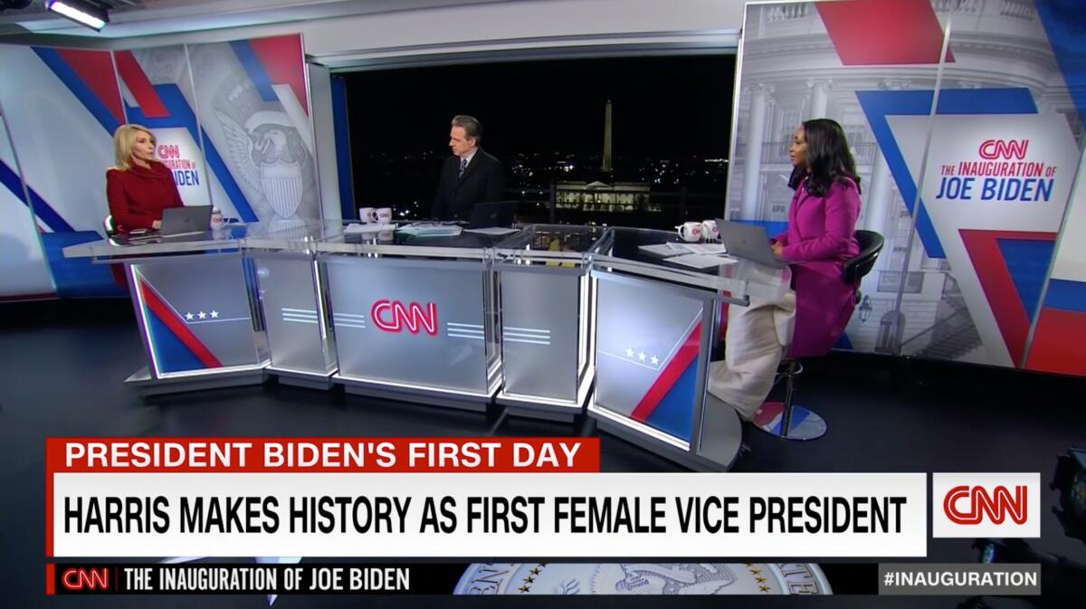 Three people sit at a desk at CNN during coverage of President Biden's inauguration in 2021.