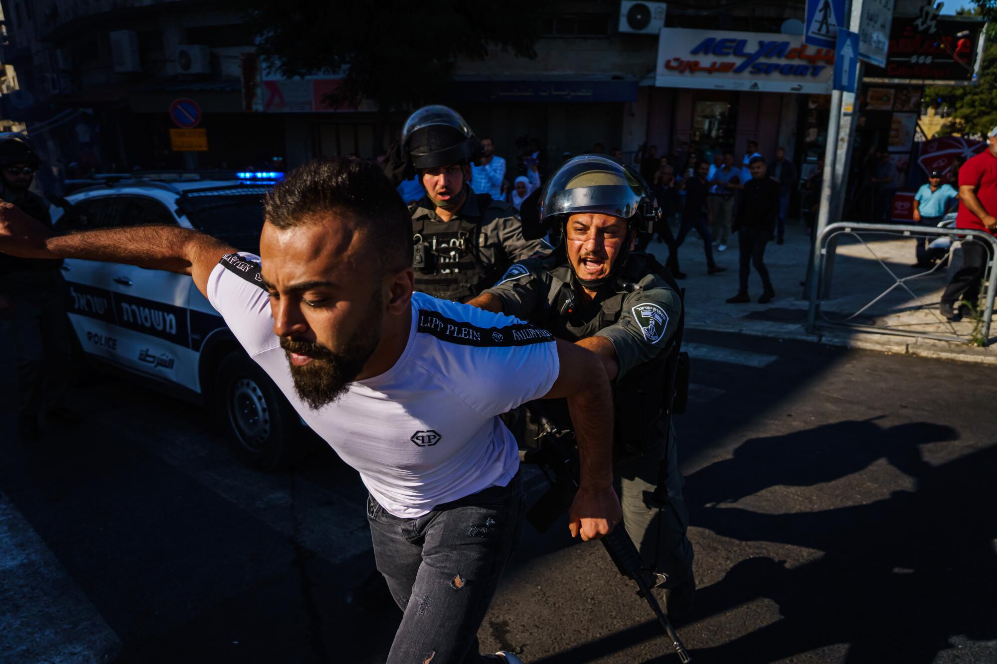 A pedestrian is shoved out of the way as Israeli security forces disperse a crowd.