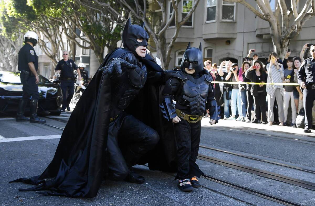 Five-year-old cancer survivor Miles Scott, dressed as Batkid, walks with Batman before saving a damsel in distress in San Francisco on Friday.