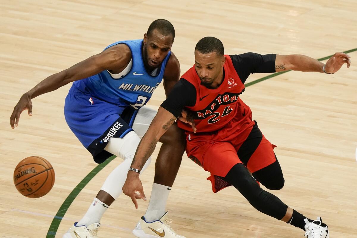 Milwaukee Bucks' Khris Middleton and Toronto Raptors' Norman Powell go after a loose ball.