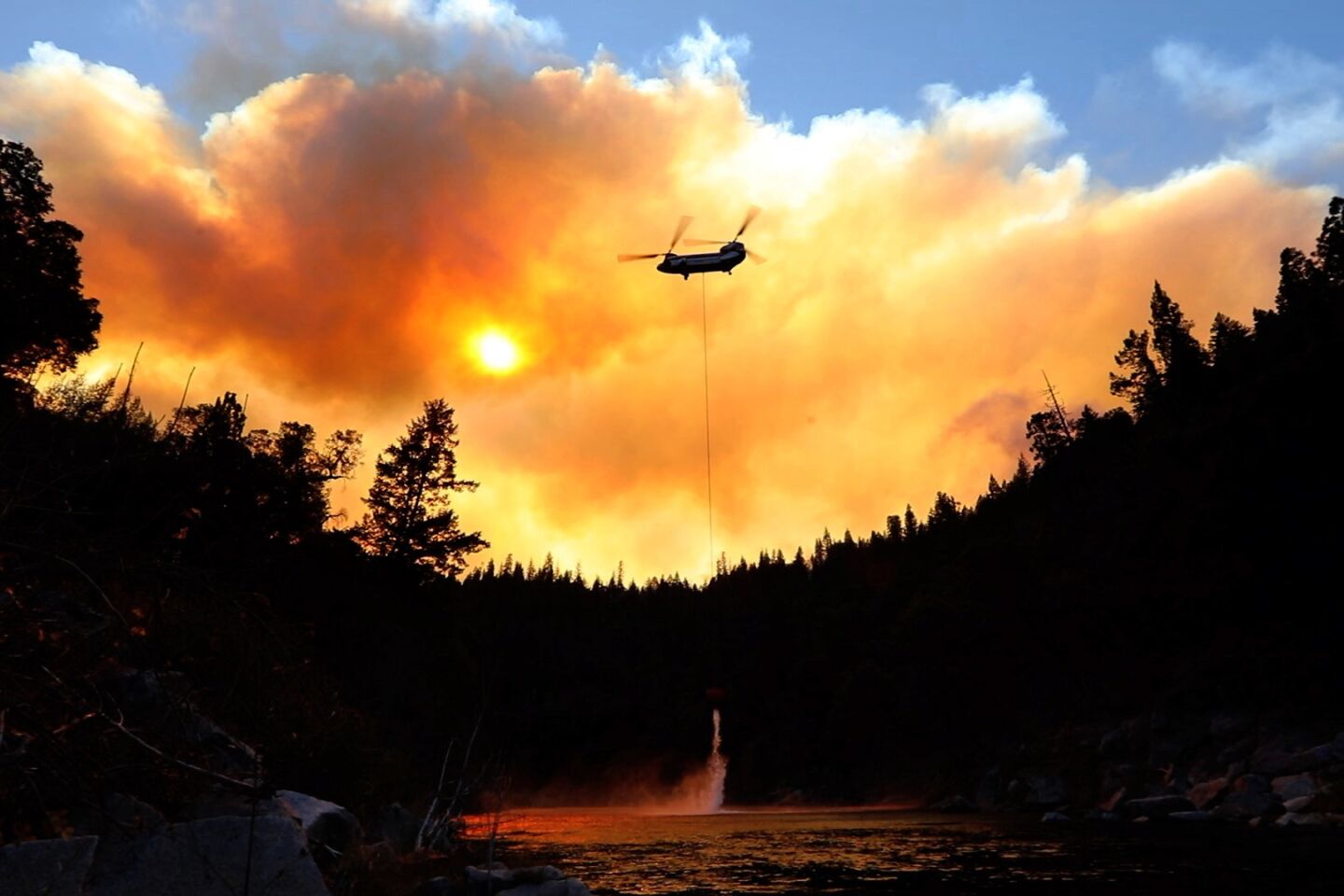 Outside of Pulga, Calif., on the North Fork of the Feather River, where the Camp fire may have started, helicopters do airdrops while ground crews try to keep the fire from spreading.