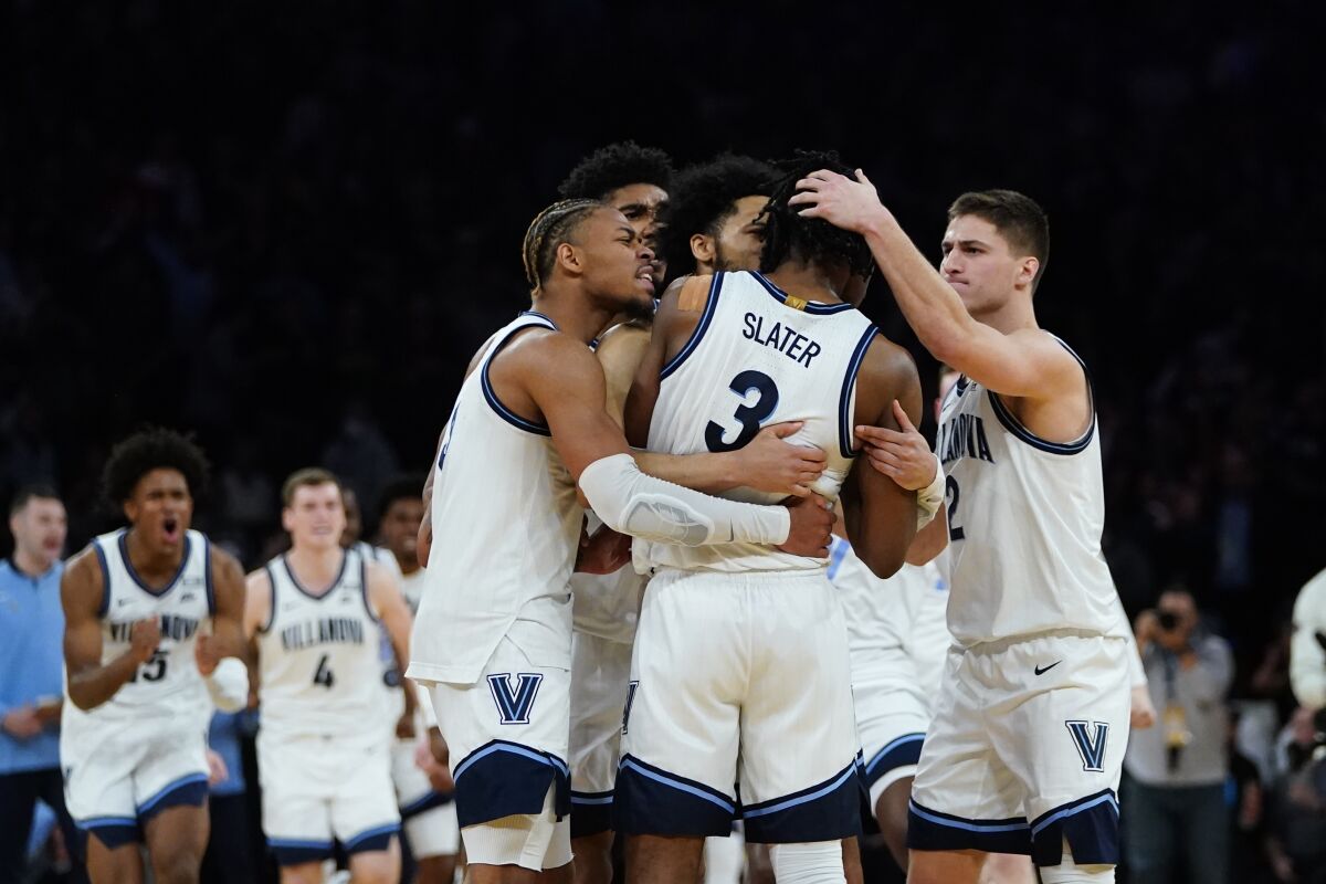 Villanova's Collin Gillespie, right, and Justin Moore, left, celebrate with Brandon Slater after the team's win over St. John's in an NCAA college basketball game during the Big East men's tournament Thursday, March 10, 2022, in New York. Villanova won 66-65. (AP Photo/Frank Franklin II)