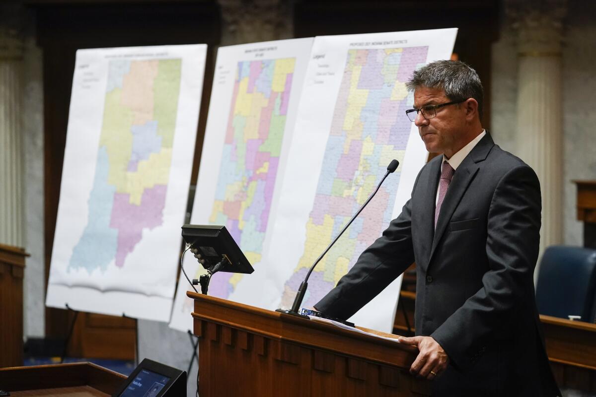 Indiana Senate President Pro Tem Rodric Bray speaks at a lectern near redistricting maps.