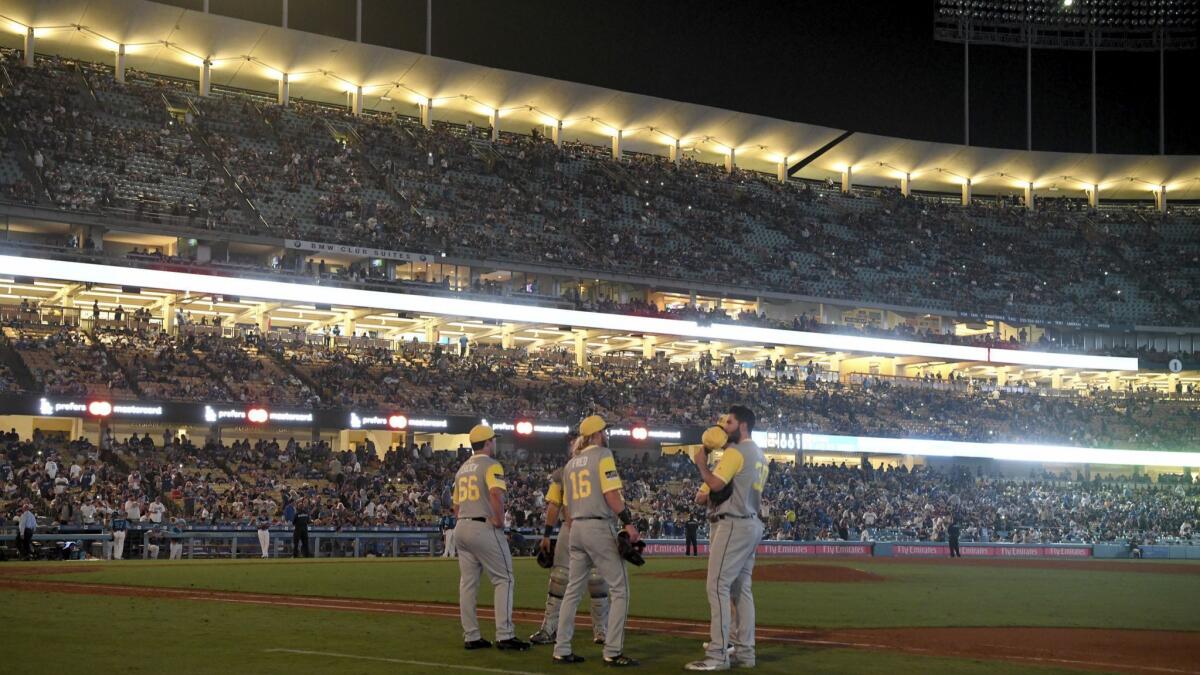 Several San Diego Padres players gather in the infield during a blackout in the 12th inning of a baseball game against the Los Angeles Dodgers,