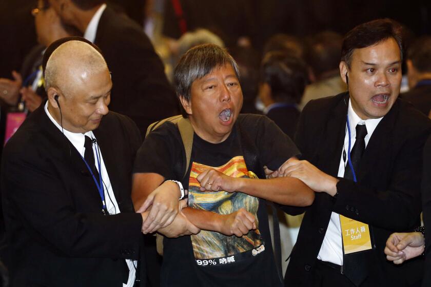 Pro-democracy lawmaker Lee Cheuk-yan, center, is taken away by security guards after a protest against Li Fei, deputy secretary general of China's National People's Congress standing committee, in Hong Kong on Monday.