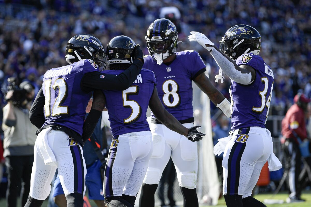 Baltimore Ravens quarterback Lamar Jackson (8) reacts after throwing a touchdown pass to wide receiver Marquise Brown (5) during the second half of an NFL football game against the Cincinnati Bengals, Sunday, Oct. 24, 2021, in Baltimore. Ravens' Rashod Bateman (12) and Ty'Son Williams (34) join in on the celebration. (AP Photo/Nick Wass)
