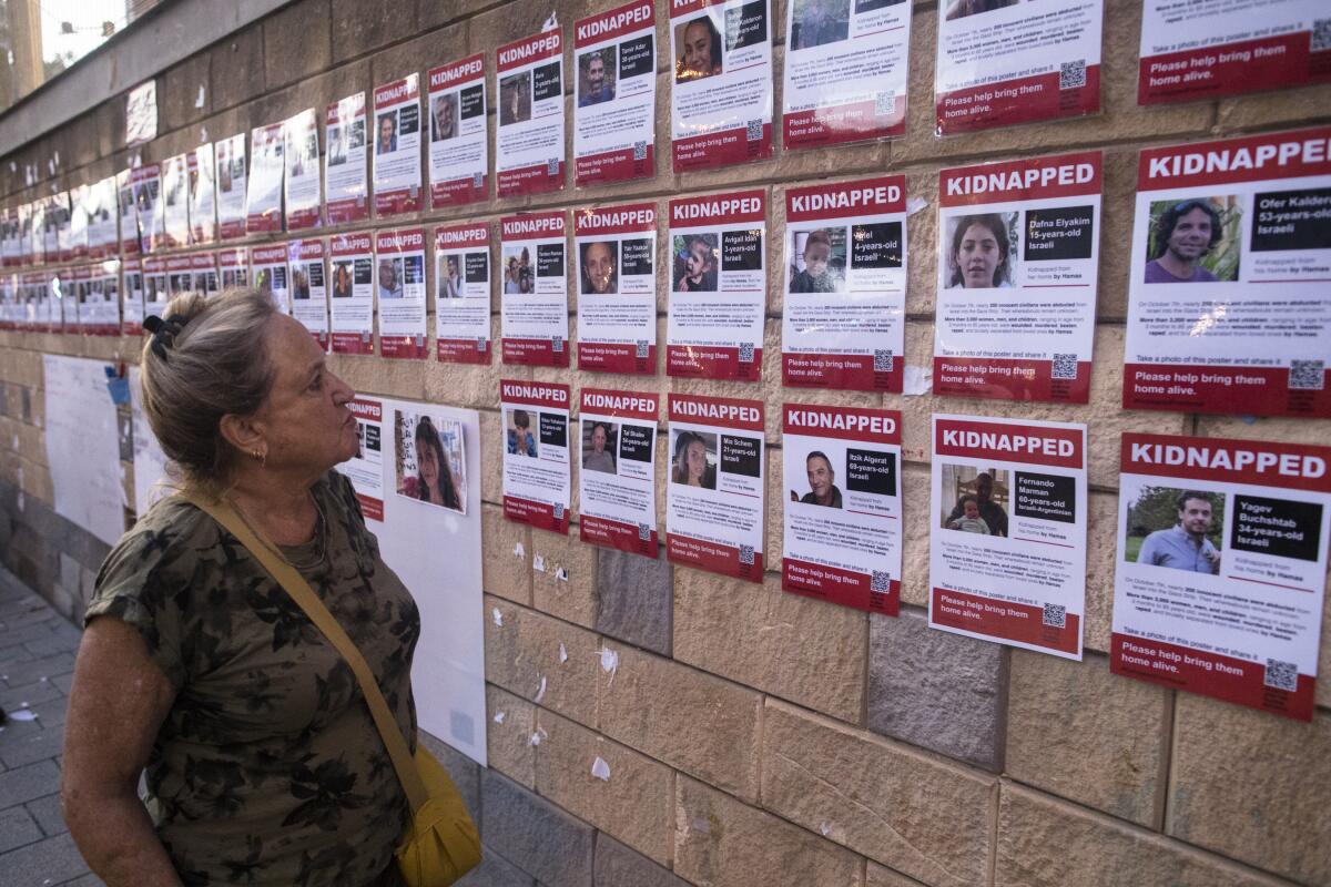 A woman looks at a wall with photos of hostages kidnapped and taken to Gaza in the Hamas attack on Israel.