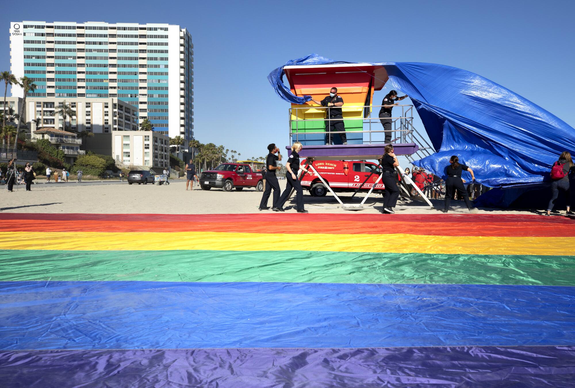 A tarp covering a rainbow lifeguard tower is blown in the wind