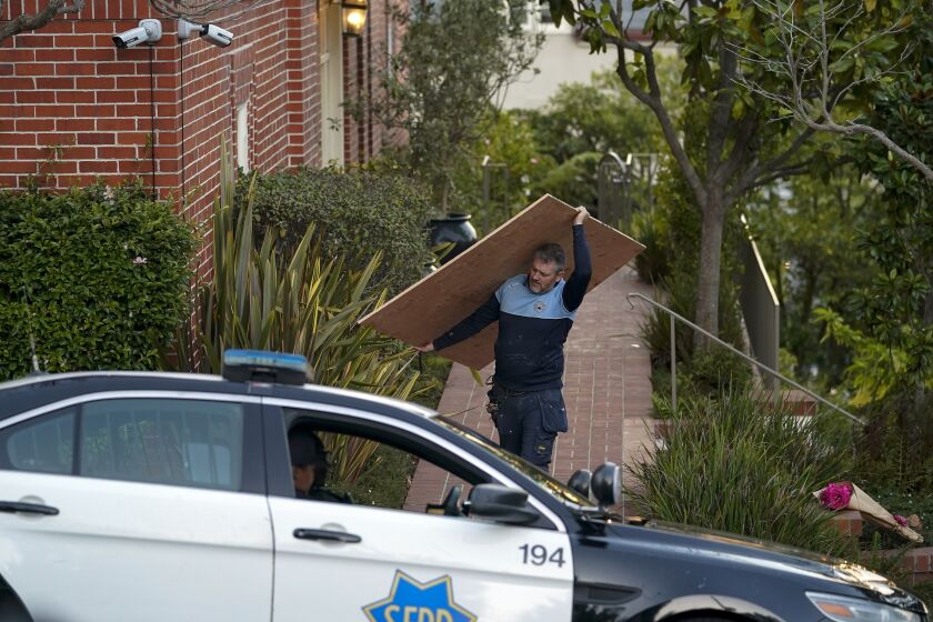 A worker carries a sheet of plywood from the home of Paul Pelosi, the husband of House Speaker Nancy Pelosi, in San Francisco, Friday, Oct. 28, 2022. Paul Pelosi, was attacked and severely beaten by an assailant with a hammer who broke into their San Francisco home early Friday, according to people familiar with the investigation. (AP Photo/Godofredo A. Vásquez)