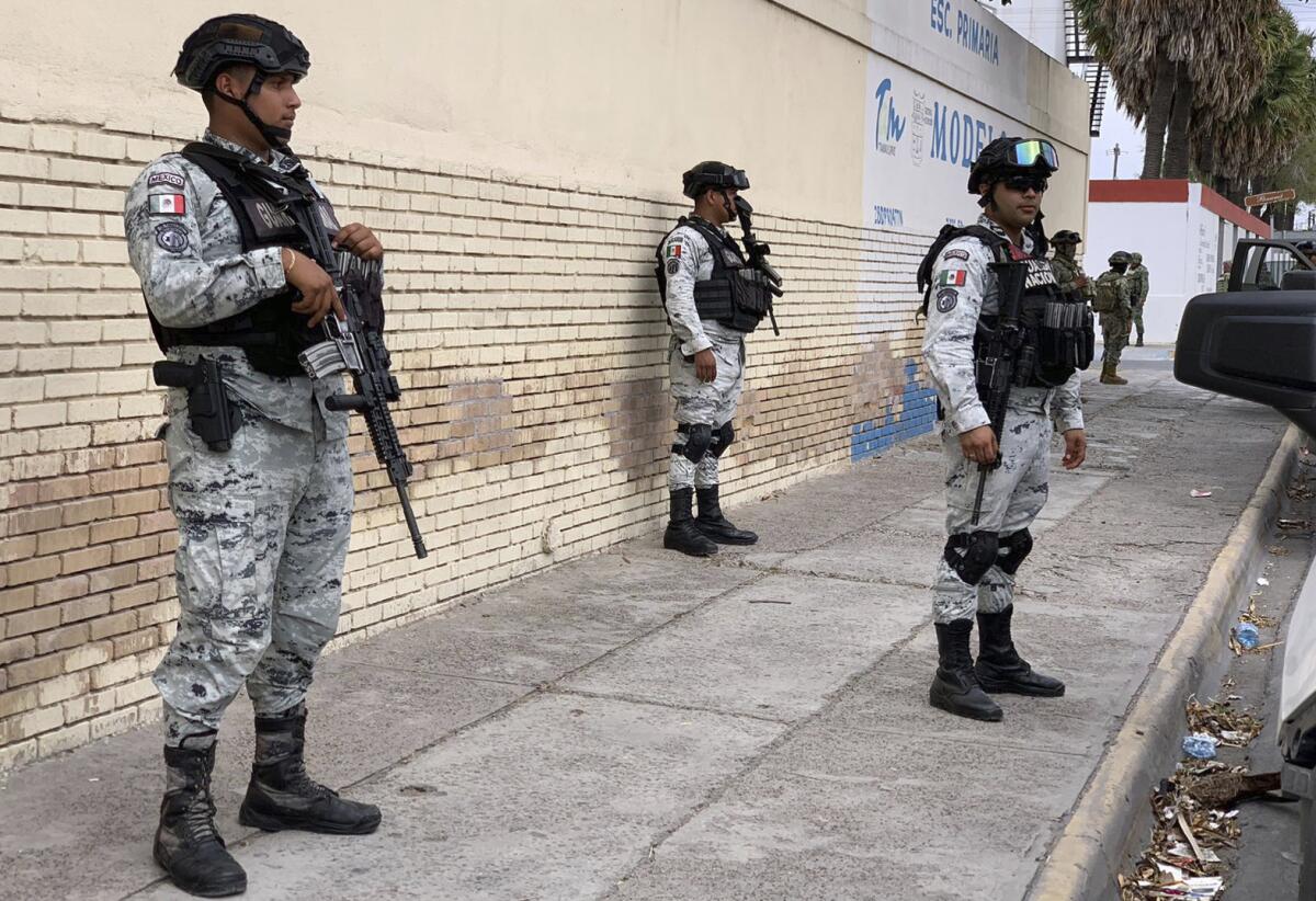 Armed security officers stand on a sidewalk