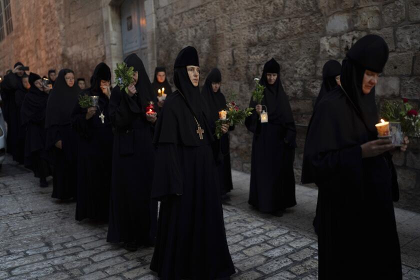 FILE - Christian orthodox nuns hold candles and flowers as they walk in a procession to bring an icon of the Virgin Mary to the tomb where it is believed she is buried, along the streets of the Old City of Jerusalem, early Friday, Aug. 25, 2023. Since Israel’s most right-wing government in history came to power late last year, concerns have mounted among religious leaders over the increasing harassment of the region’s 2,000-year-old Christian community. (AP Photo/Ohad Zwigenberg, File)