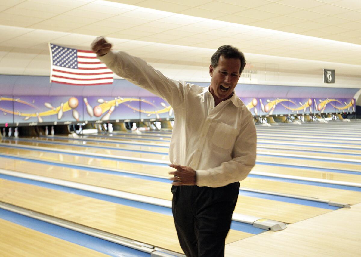 Rick Santorum, who won Saturday's Republican presidential primary in Louisiana, celebrates a strike while bowling after a campaign rally in Sheboygan, Wis.