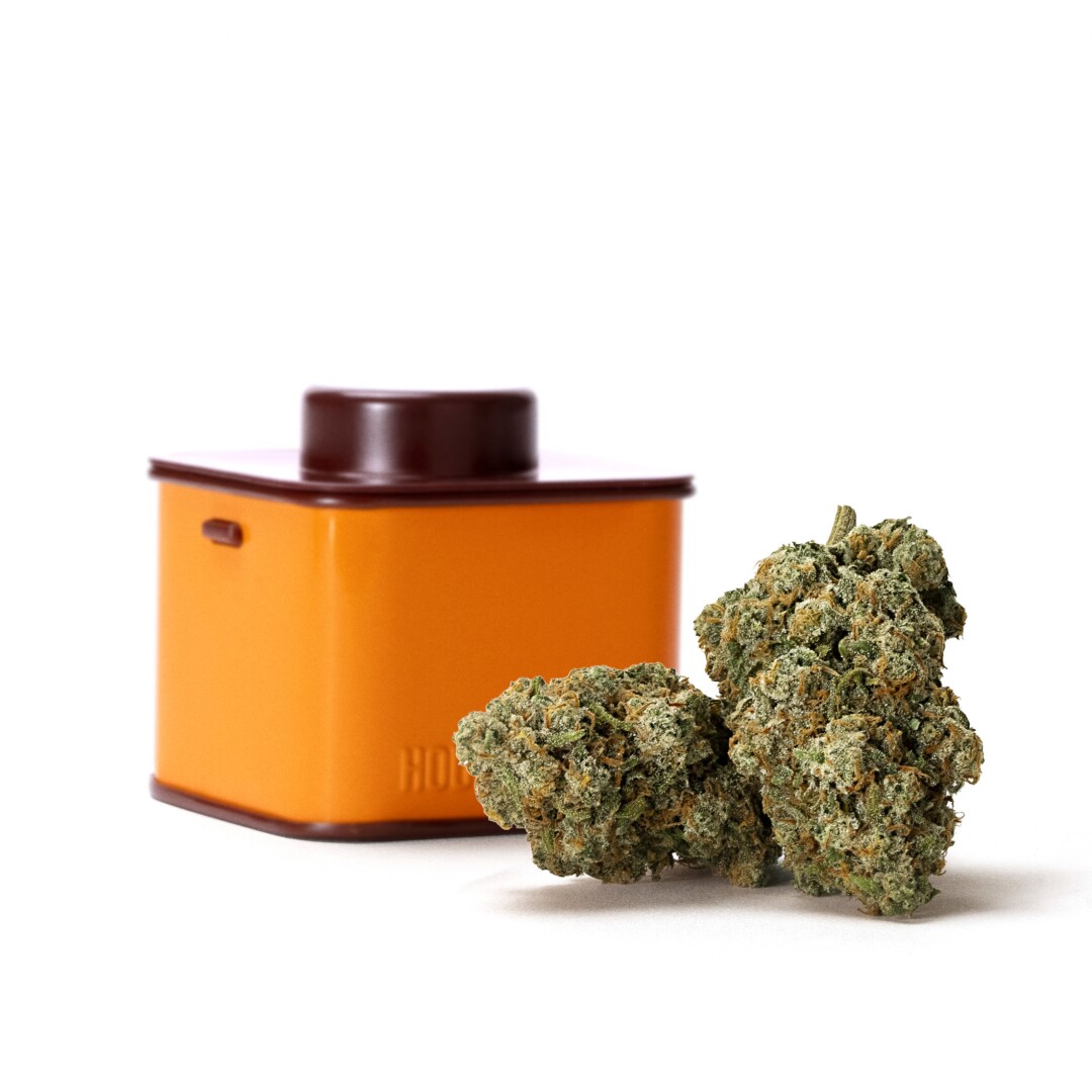 An orange tin next to a cannabis nugget.