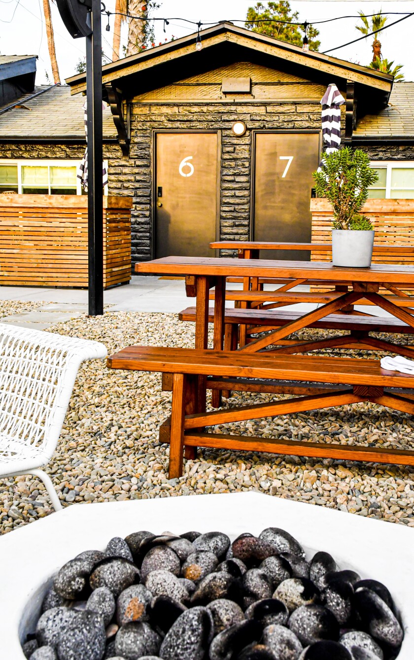 A fire pit and picnic table with hotel doors in the background.