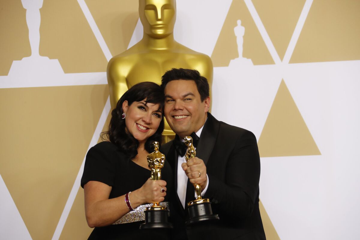 Kristen Anderson-Lopez and Robert Lopez hold their Academy Awards for original song, "Remember Me" from "Coco."