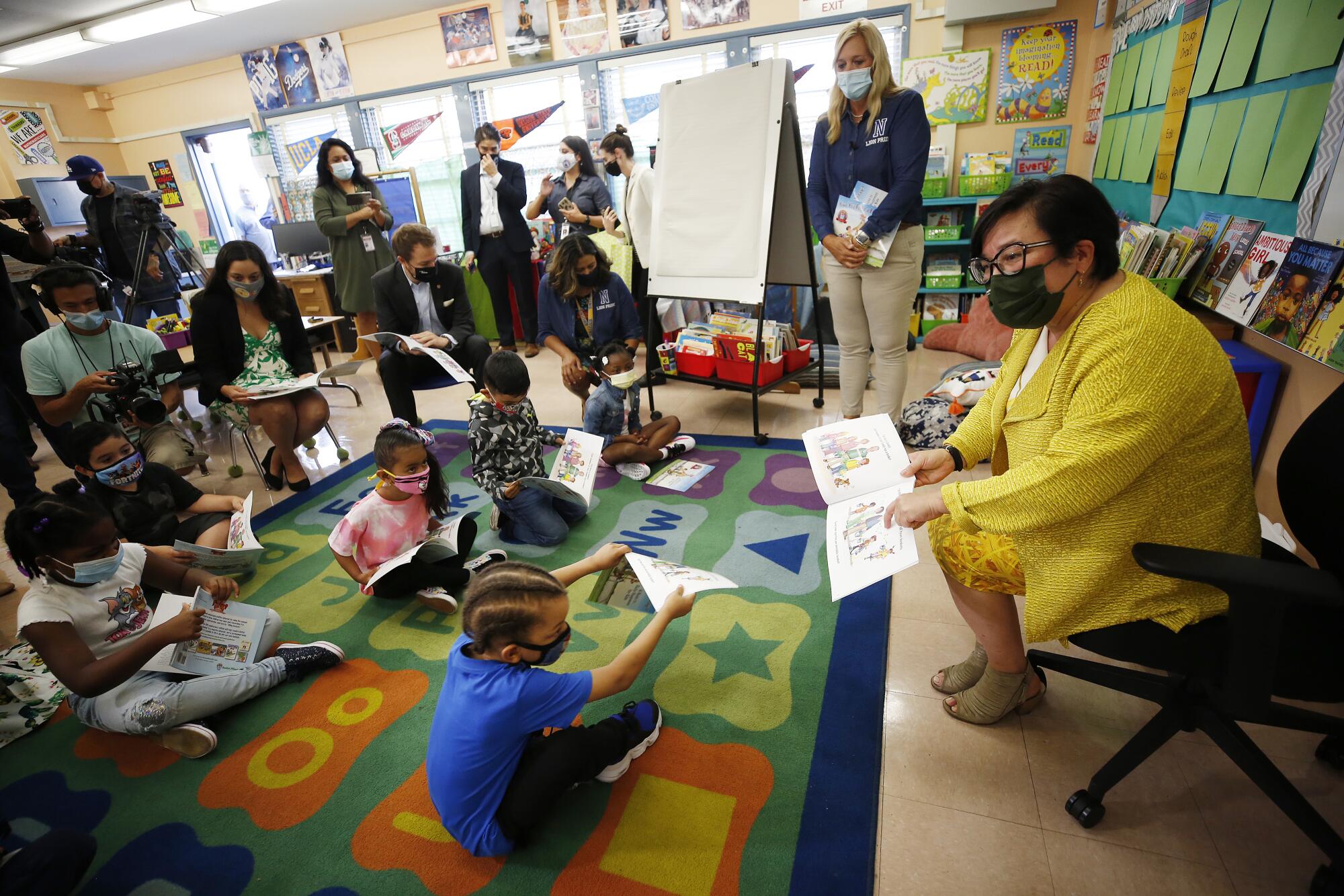 Interim Superintendent Megan K. Reilly reads to students who are sitting on a colorful rug