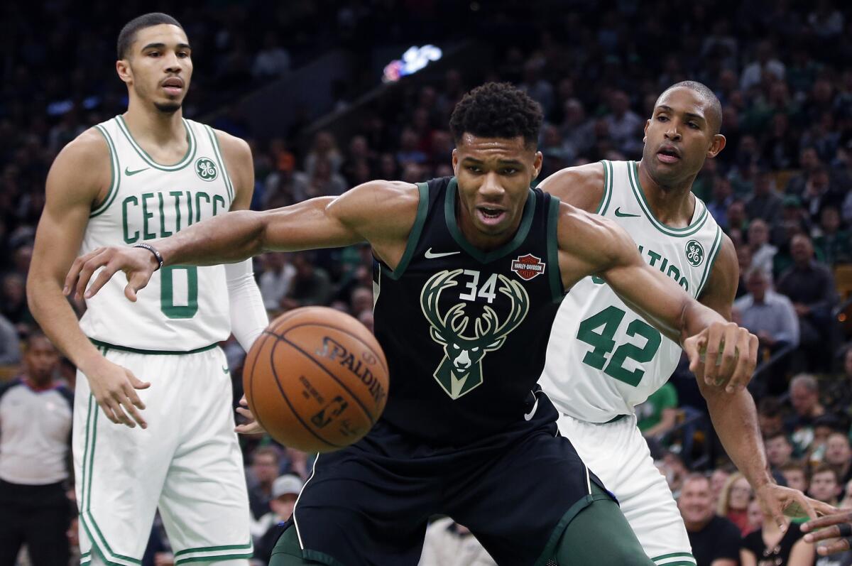 Bucks forward Giannis Antetokounmpo, center, tries to fend off Celtics forward Jayson Tatum, left, and center Al Horford while tracking down a loose ball during a Nov. 1 game.