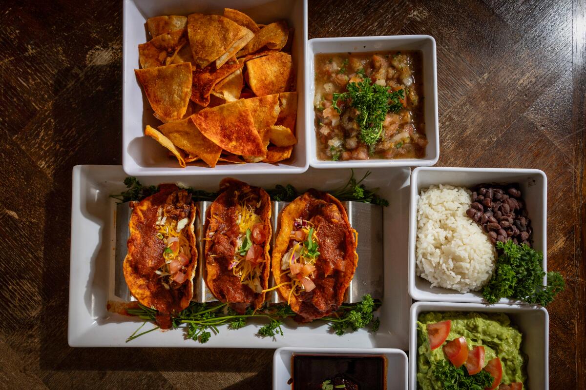 Containers with tacos, chips, beans and rice and other dishes.