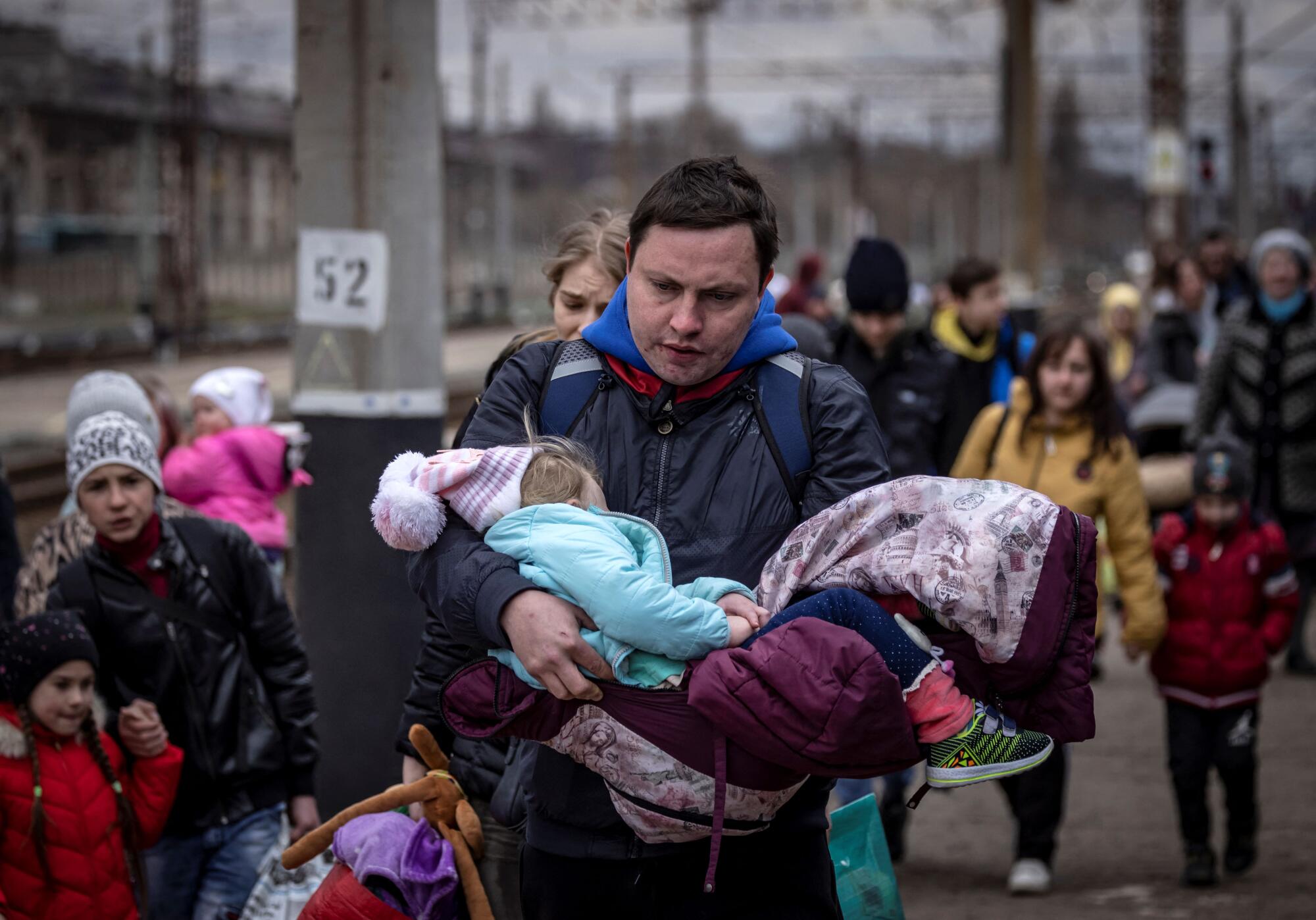 A man carries a little girl as he arrives with other families to board a train at Kramatorsk central station.