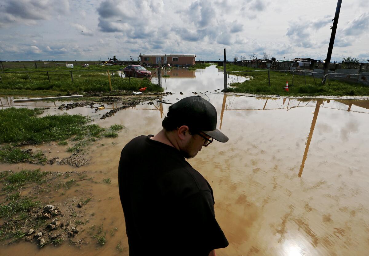 A man stands in a flooded yard. 