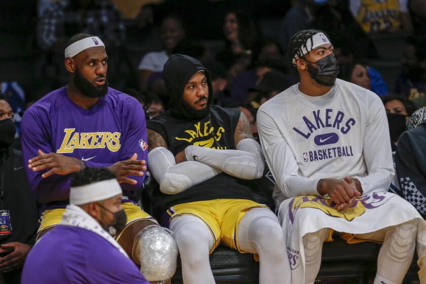Los Angeles Lakers forwards LeBron James (6), Carmelo Anthony (7) and Anthony Davis (3) watch on the bench during the second half of a preseason NBA basketball game against the Golden State Warriors in Los Angeles, Tuesday, Oct. 12, 2021. (AP Photo/Ringo H.W. Chiu)