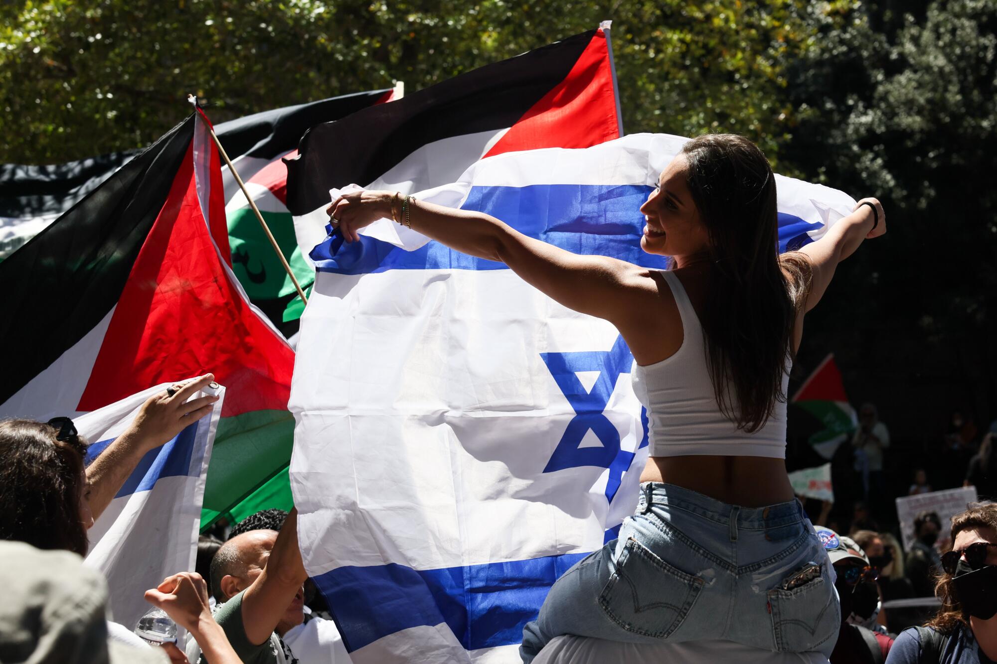 A protester in support of Israel waves an Israeli flag while surrounded by pro-Palestinian supporters. 