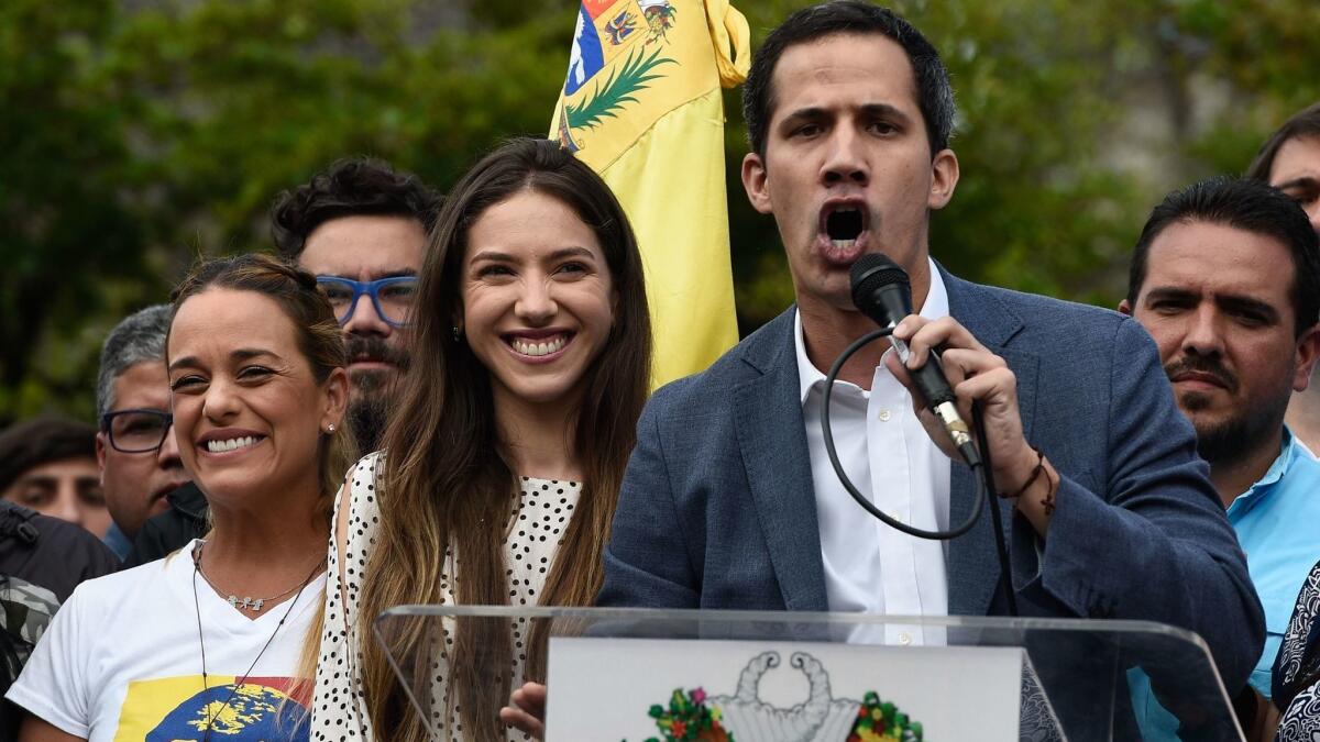 The head of Venezuela's National Assembly and the country's self-proclaimed "acting president" Juan Guaido speaks next to his wife Fabiana Rosales to a crowd of supporters in Caracas on Saturday.