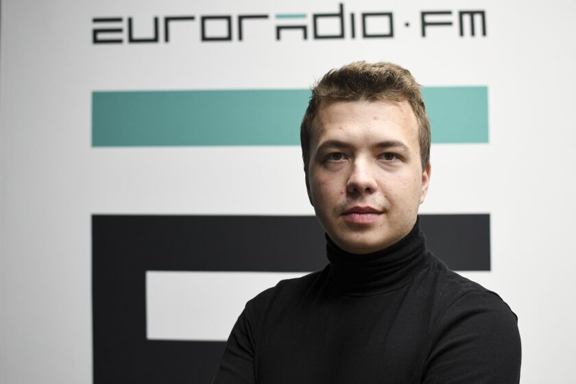 In this handout photo released by European Radio for Belarus, Belarus journalist Raman Pratasevich poses for a photo in front of euroradio.fm sign in Minsk, Belarus, Sunday, Nov. 17, 2019. Western outrage grew and the European Union threatened more sanctions Monday over the forced diversion of a plane to Belarus in order to arrest an opposition journalist. The dramatic gambit apparently ordered by the country's authoritarian president to suppress dissent was denounced as piracy, a hijacking and terrorism. (Euroradio via AP)
